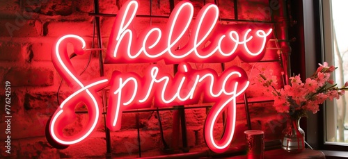 "Hello Spring" neon sign with pink blossoms on a windowsill