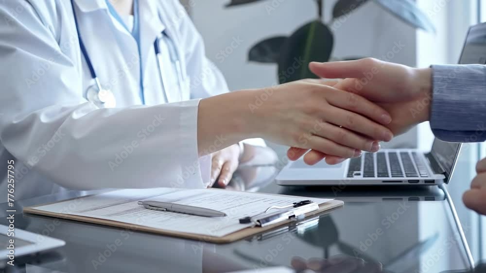 Doctor and patient handshake in clinic setting above the glass table. Medicine concept trust and agreement Doctor and patient handshake in clinic setting above the glass table. Medicine concept trust and agreement