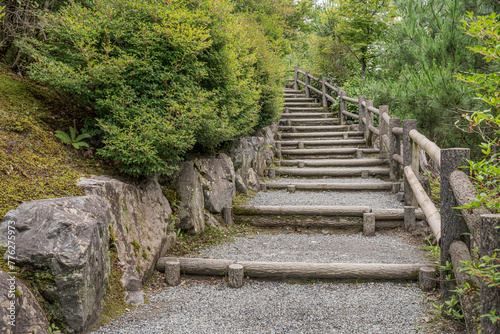 Pebble walkway stairs in a Japanese Zen garden. Winding serene walkway among lush plants. 