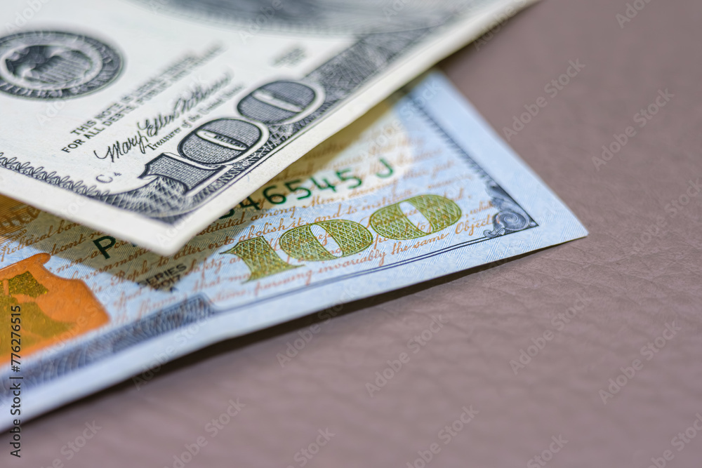 Close-up of US Dollar Bills on Surface. A detailed close-up capture of American currency, highlighting the intricate designs of the hundred-dollar bills. Selective focus Close-up of US Dollar Bills on Surface. A detailed close-up capture of American currency, highlighting the intricate designs of the hundred-dollar bills. Selective focus