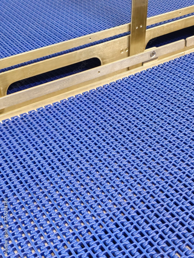 A close-up of a blue polyurethane belt in modular industrial conveyor system. Stainless steel transport systems in industrial factories.