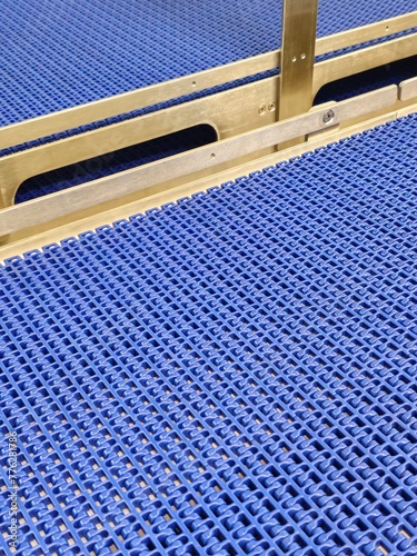 Obraz na płótnie A close-up of a blue polyurethane belt in modular industrial conveyor system. Stainless steel transport systems in industrial factories. w salonie