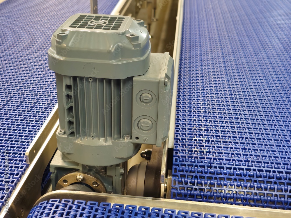 Electric motors in the stainless steel conveyor system with polyurethane, modular belt. Transport systems in industrial factories.