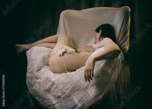 woman without clothes lying in an armchair on lace and tulle in a romantic attitude VI