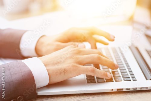 Businessman hand typing on computer keyboard of a laptop computer in office.