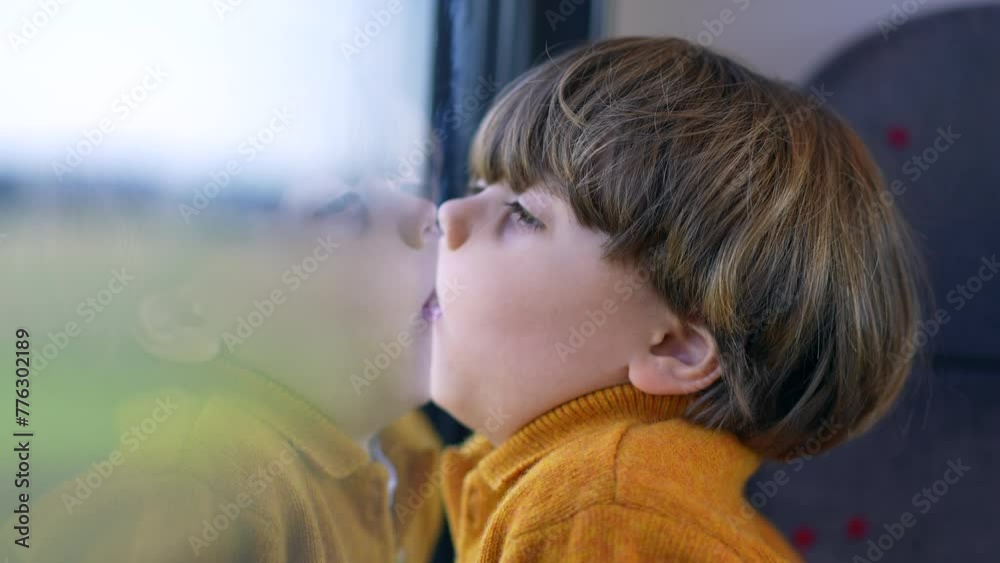 Bored funny small boy with face glued on trian window. Mouth and lips pressed on glass and staring at landscape scenery pass by in transportation Bored funny small boy with face glued on trian window. Mouth and lips pressed on glass and staring at landscape scenery pass by in transportation