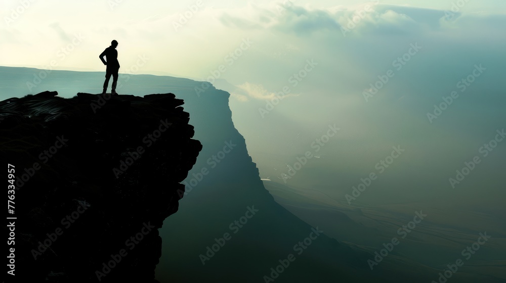 man on the mountaintop with steep rocks and white clouds
