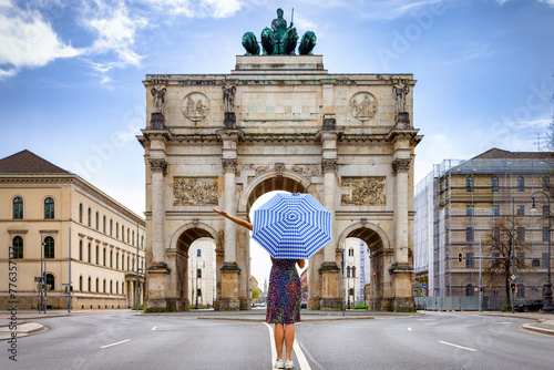 Munich travel concept with a tourist woman holding an umbrella in front of the Victory Gate, Germany photo