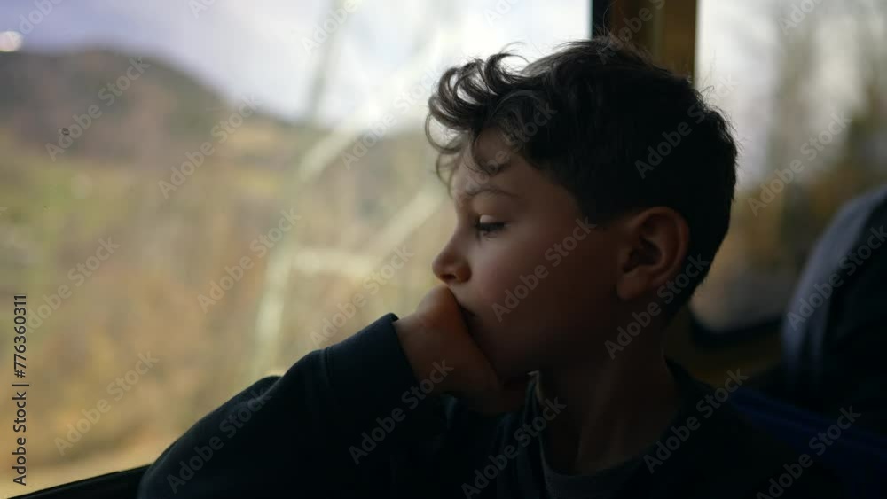 Pensive child by train window staring at mountain view from above with thoughtful expression. Young boy travels by railroad transportation looking out Pensive child by train window staring at mountain view from above with thoughtful expression. Young boy travels by railroad transportation looking out