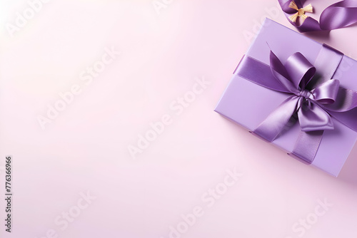 Gift box with purple ribbon and bow on pink background. copy space