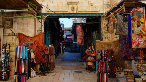 The alleys of Jerusalem's market brim with vibrant tapestries and an array of colorful fabrics, reflecting the rich cultural tapestry of the city. © Regina