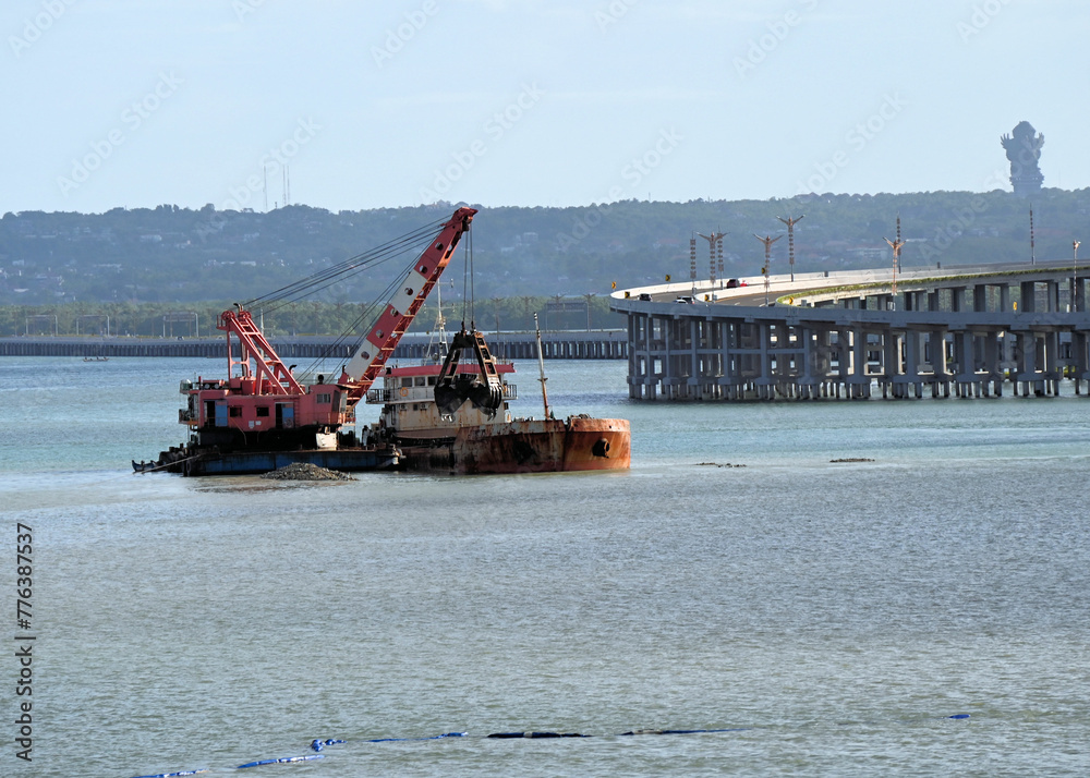 Dredging Operation in Ocean with Nearby Raised Highway and Mountains in