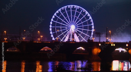 Beleuchtetes Riesenrad vor Nachthimmel am Ufer der Elbe