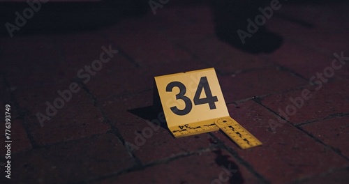 Crime scene, investigation and blood on floor for evidence, forensics and dna for pathology research. Marker, security and yellow sign with number for warning, caution and incident on red bricks