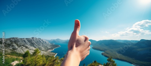 A person standing on top of a mountain with their arm extended and pointing their index finger towards the camera