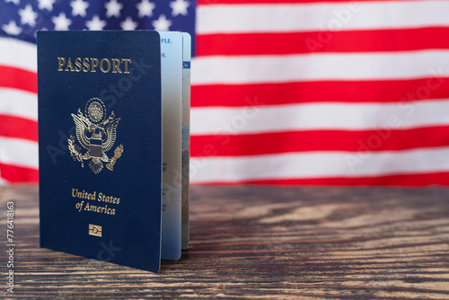 US citizen passport on a wooden table against the background of the American flag. Space for text.