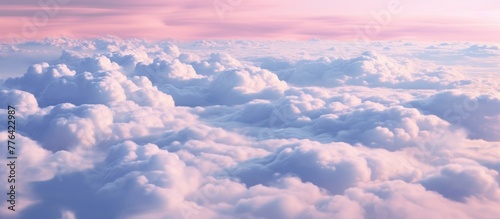 Fluffy white clouds are floating peacefully in the sky, creating a striking contrast with the pastel colors of the pink and blue sky