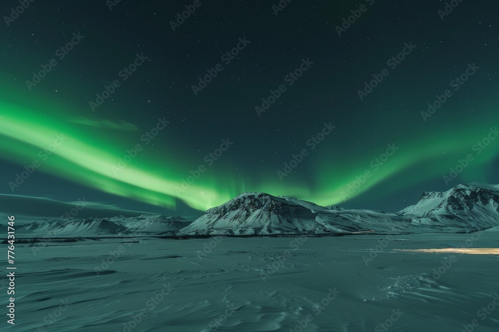 Scenic view of green auroral lights streaked at night against clear skies over snow-capped mountains