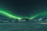 Scenic view of green auroral lights streaked at night against clear skies over snow-capped mountains