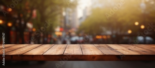 A wooden table top is shown with a blurred backdrop of city lights shining in the distance