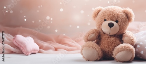 Cute teddy bear sitting comfortably on a bed covered with a soft pink blanket