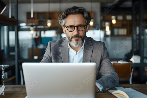 Professioneller Geschäftsmann mittleren Alters, CEO, Investor, Vielbeschäftigter älterer, reifer Geschäftsmann, Unternehmer im Anzug sitzt am Schreibtisch und benutzt Laptop photo