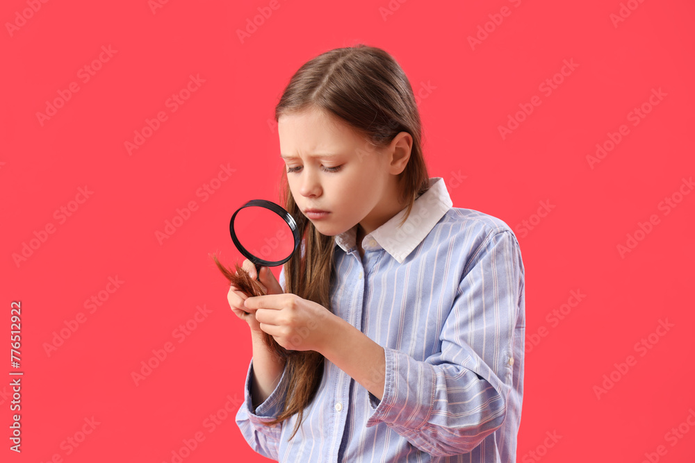 Sad little girl with magnifier looking at her hair on red background Sad little girl with magnifier looking at her hair on red background