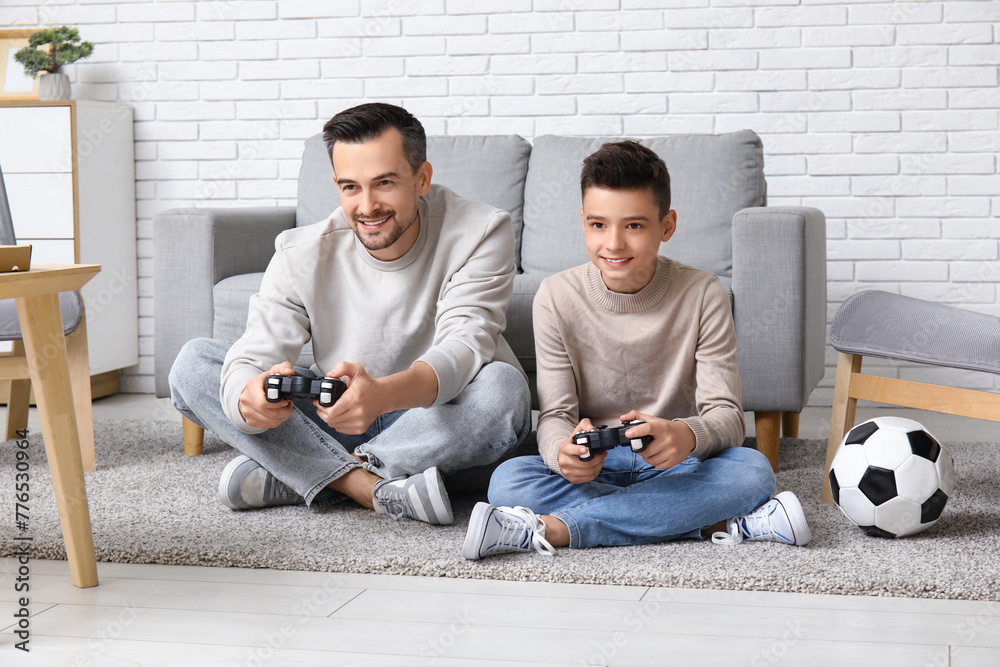 Father and his little son with soccer ball playing video games at home - obrazy, fototapety, plakaty 