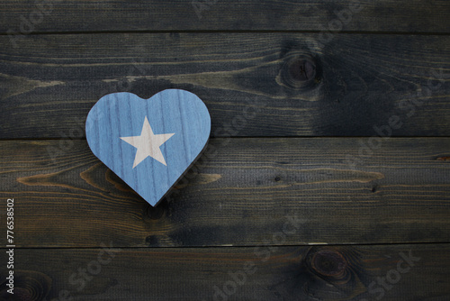 wooden heart with national flag of somalia on the wooden background.