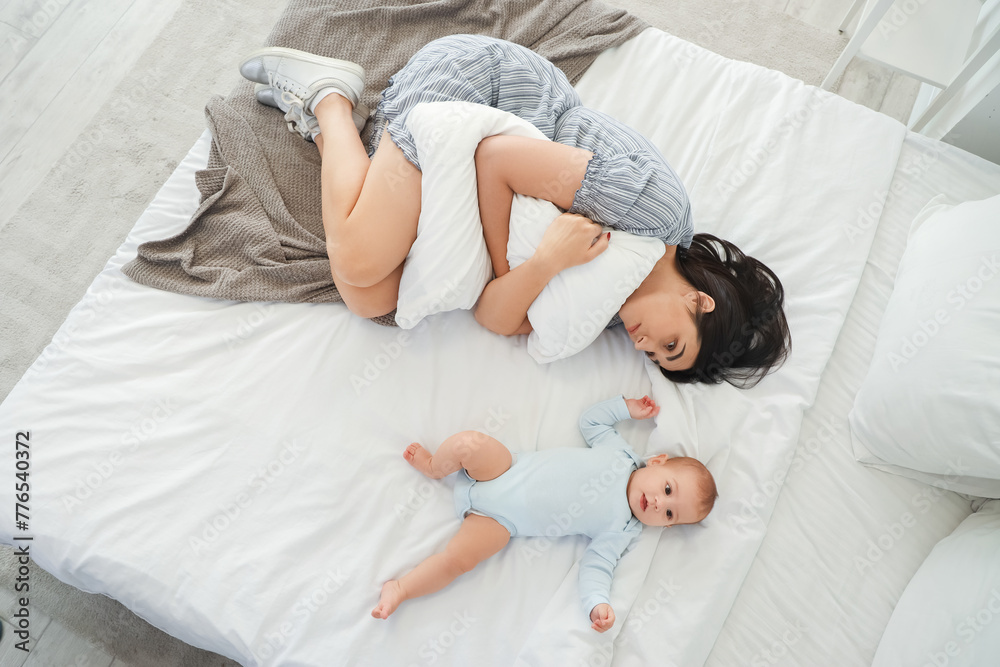 Naklejka premium Young woman with her baby suffering from postnatal depression on bed, top view