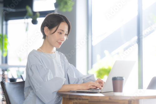 Business scene with a close-up of a smiling beautiful Asian (Japanese) woman working at a computer in a beautiful office or cafe in profile. Free Download Business scene with a close-up of a smiling beautiful Asian (Japanese) woman working at a computer in a beautiful office or cafe in profile. - GFXLoad