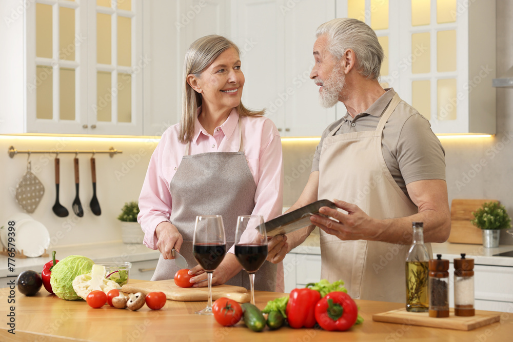 Happy senior couple cooking together in kitchen Happy senior couple cooking together in kitchen