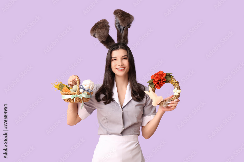 Shocked female chambermaid in bunny ears with Easter basket and wreath on purple background