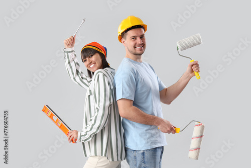 Young couple with tools on light background. Repair concept
