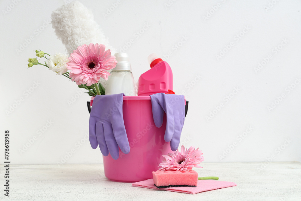 Bucket with cleaning supplies, tools and spring flowers on white background - obrazy, fototapety, plakaty 