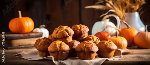 A close up of a variety of freshly baked muffins displayed on a table alongside decorative pumpkins