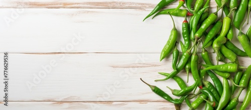 Fresh green chili peppers neatly arranged on a rustic white wooden surface for a vibrant and natural display photo