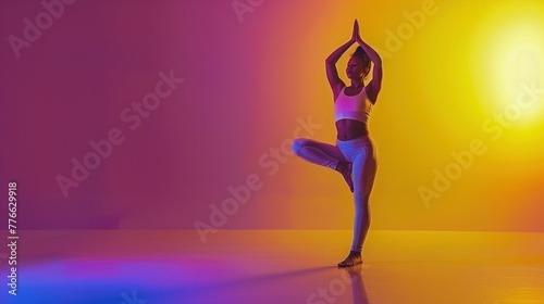 A woman doing a yoga pose on a stage with ligting in shades of purple and yellow