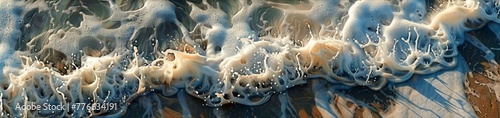 a close-up of the intricate patterns and textures of a wave as it recedes from the shore, leaving behind a canvas of foam and sand. photo