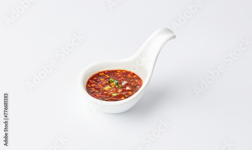 Thai chili sauce (Nam jim jaew) served on white spoon cup isolated on white background. It’s made with fish sauce, sugar, and lime, good for grilled meats. spicy, sweet, salty and sour taste.