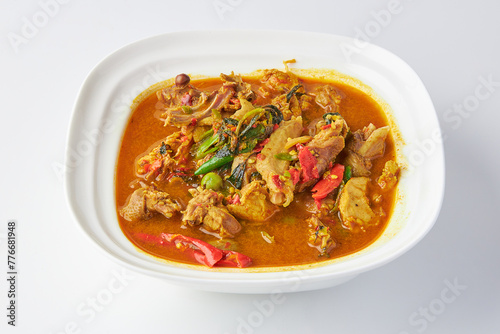 Chicken jungle curry served in white bowl isolated on white background. Hot and spicy chicken soup with herbs and vegetable Thai style. photo