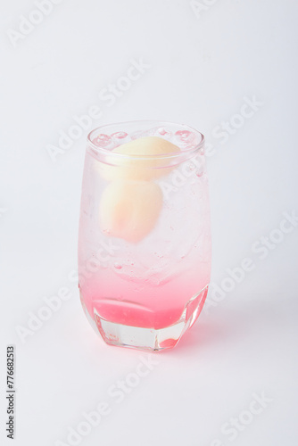 Refreshing Lychee Soda with ice topped with fresh lychee served in a clear glass isolated on white background.