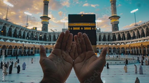 Devout Muslim praying with open hands facing the Kaaba during a serene sunset at the Grand Mosque. photo