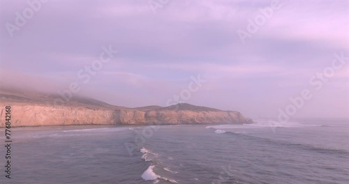 Sea waves, cliffs and lighthouse at sunset with foam near the shore. Sea surface aerial view of sea. Puerto Eten, Peru.