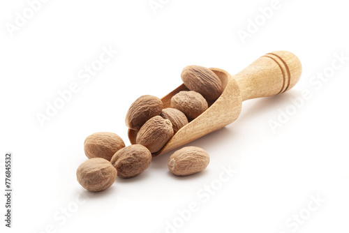 Front view of a wooden scoop filled with Organic Nutmeg seed  (Myristica fragrans). Isolated on a white background. photo