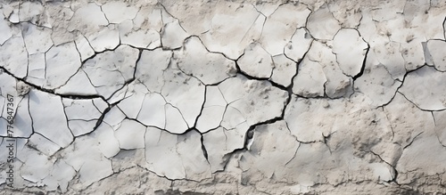 Detailed view of a white wall featuring numerous cracks and fractures running along its surface