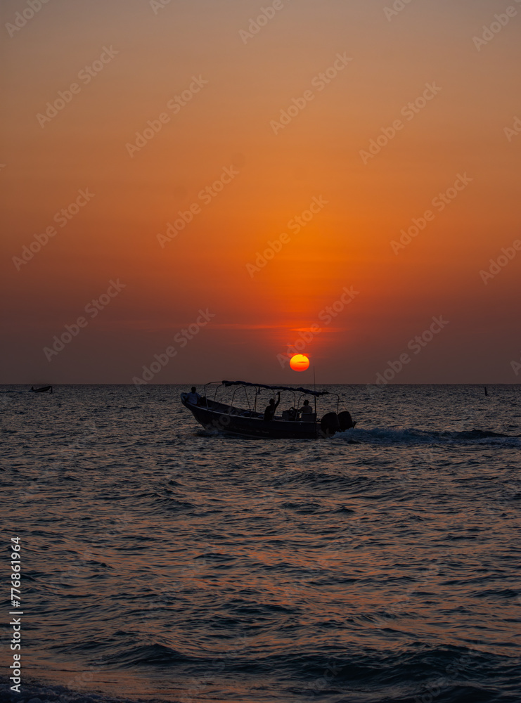 Sunset at Playa Blanca, Baru, with a boat silhouette against the tranquil sky, capturing the scenic atmosphere of Cartagena, Colombia