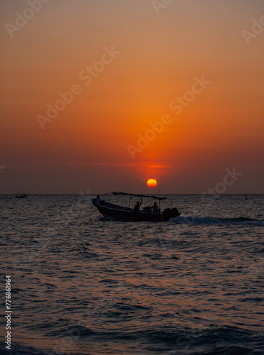 Sunset at Playa Blanca, Baru, with a boat silhouette against the tranquil sky, capturing the scenic atmosphere of Cartagena, Colombia © Jhampier