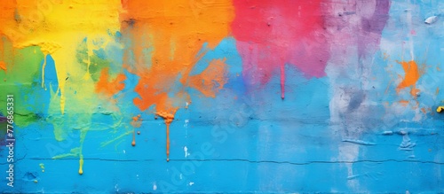 Vibrant close-up of a wall covered in a variety of colors with splashes and splatters of paint, creating a dynamic and artistic background