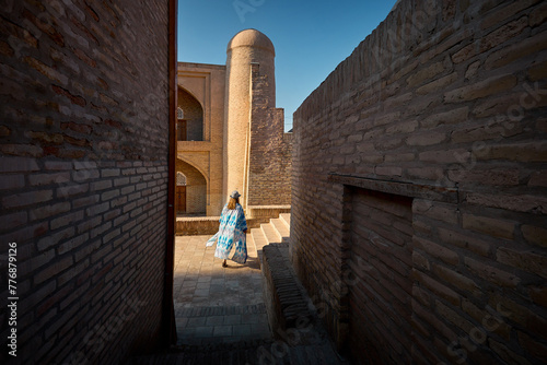 Tourist woman in ethnic dress at narrow street in Ichan Kala of Khiva
